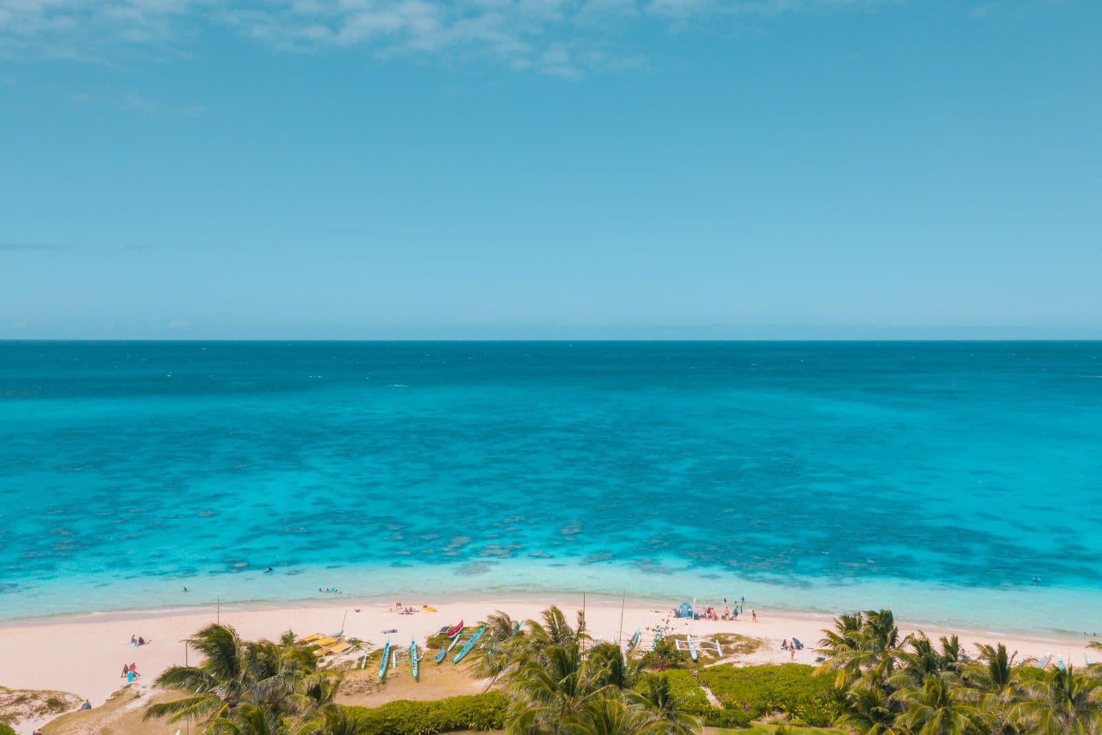 A bright, simple tropical beach photograph with turquoise water, white sand and palm trees.