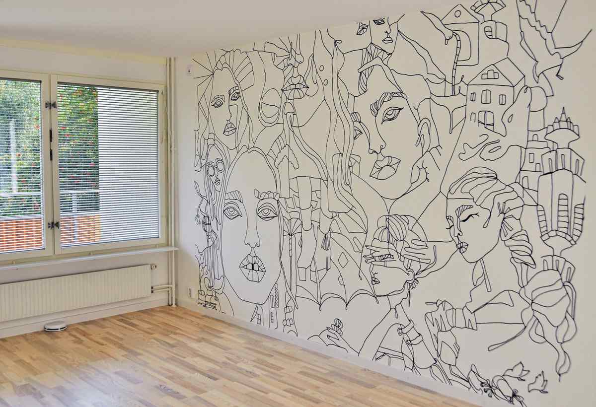 Room with a large black line-art mural of faces covering an entire wall