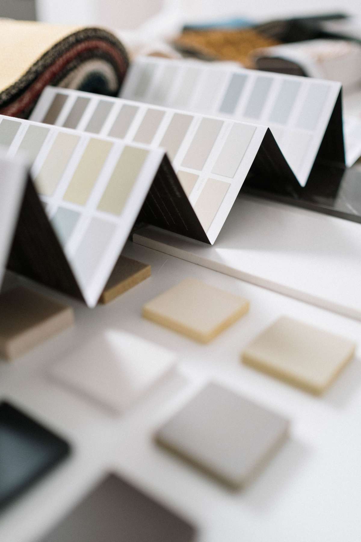 Close-up of folded paint color swatch fan decks and material sample tiles on a designer's table