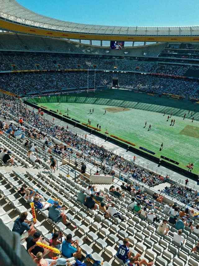 Crowded stadium stands with spectators watching a match on the field below
