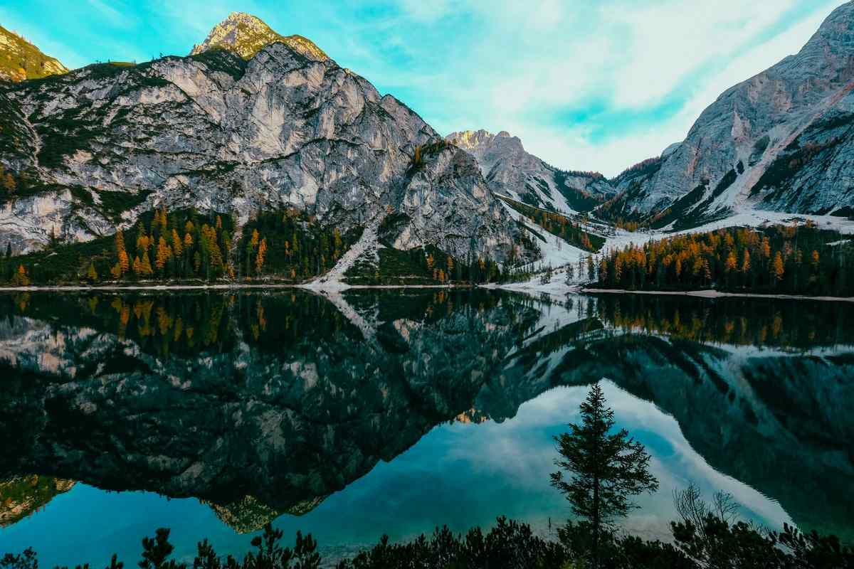Mountain peaks and autumn trees reflected in a still alpine lake