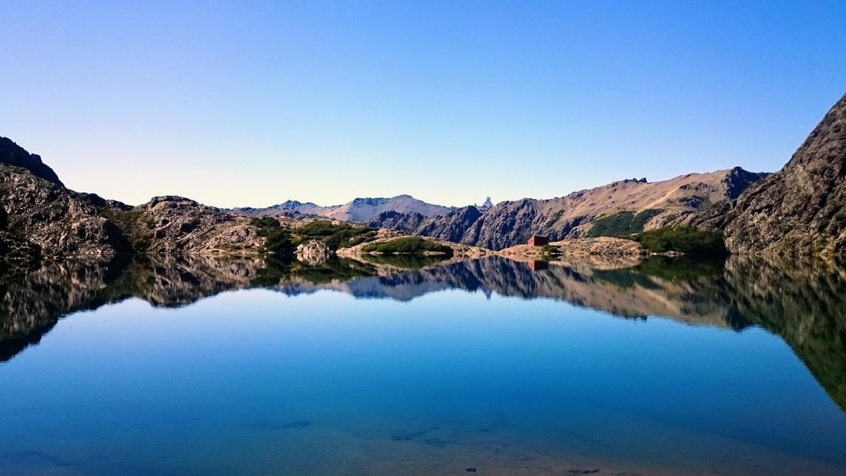 Vivid blue mountain lake photograph with a mirror reflection of rocky peaks