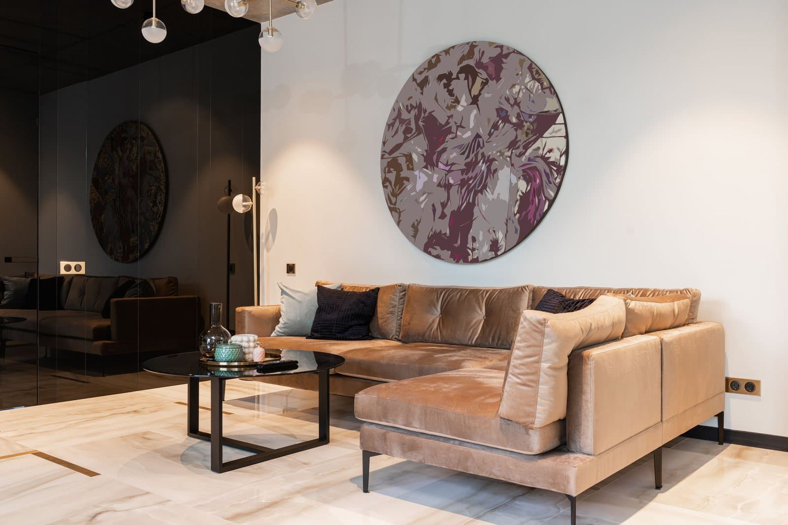 An oversized round abstract artwork anchoring the tall white wall above a tan sectional sofa in a spacious living room.