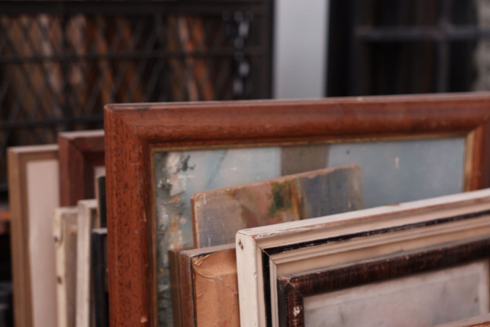 Framed paintings stored upright, stacked together in a crate.