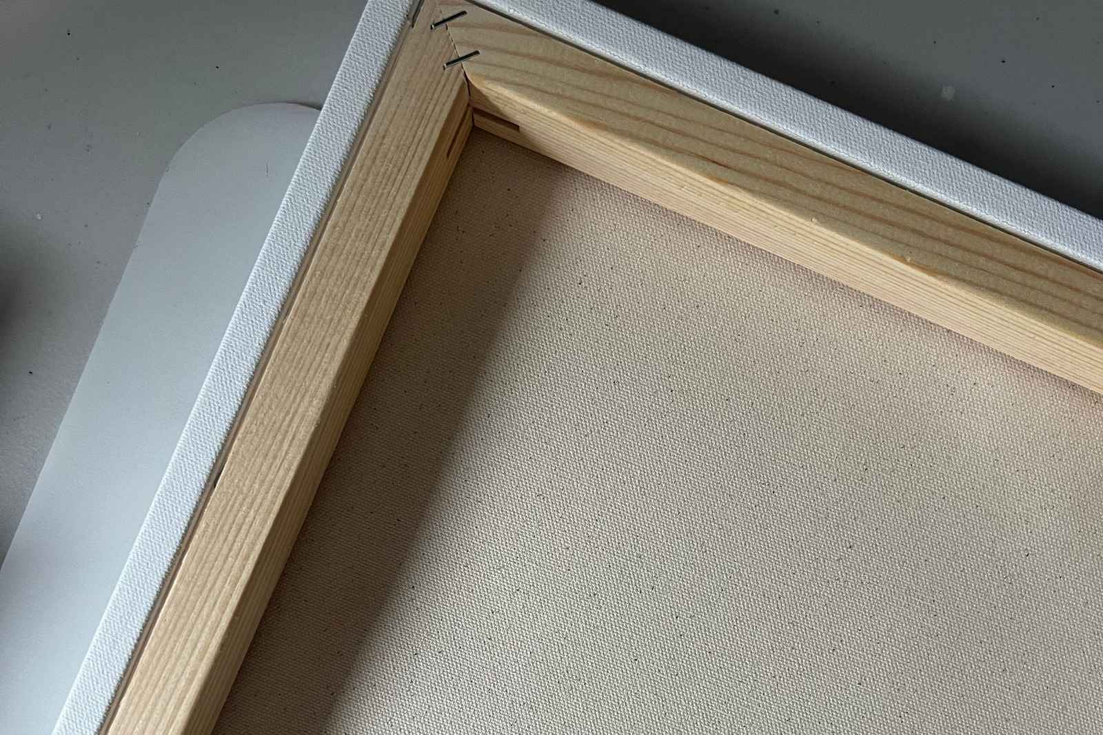 Close-up of the back corner of a canvas stretched over a wooden stretcher frame.