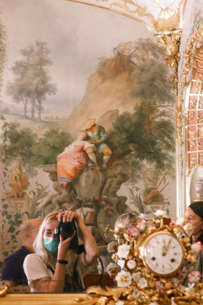 Woman photographing a large classical wall painting with a camera in a museum